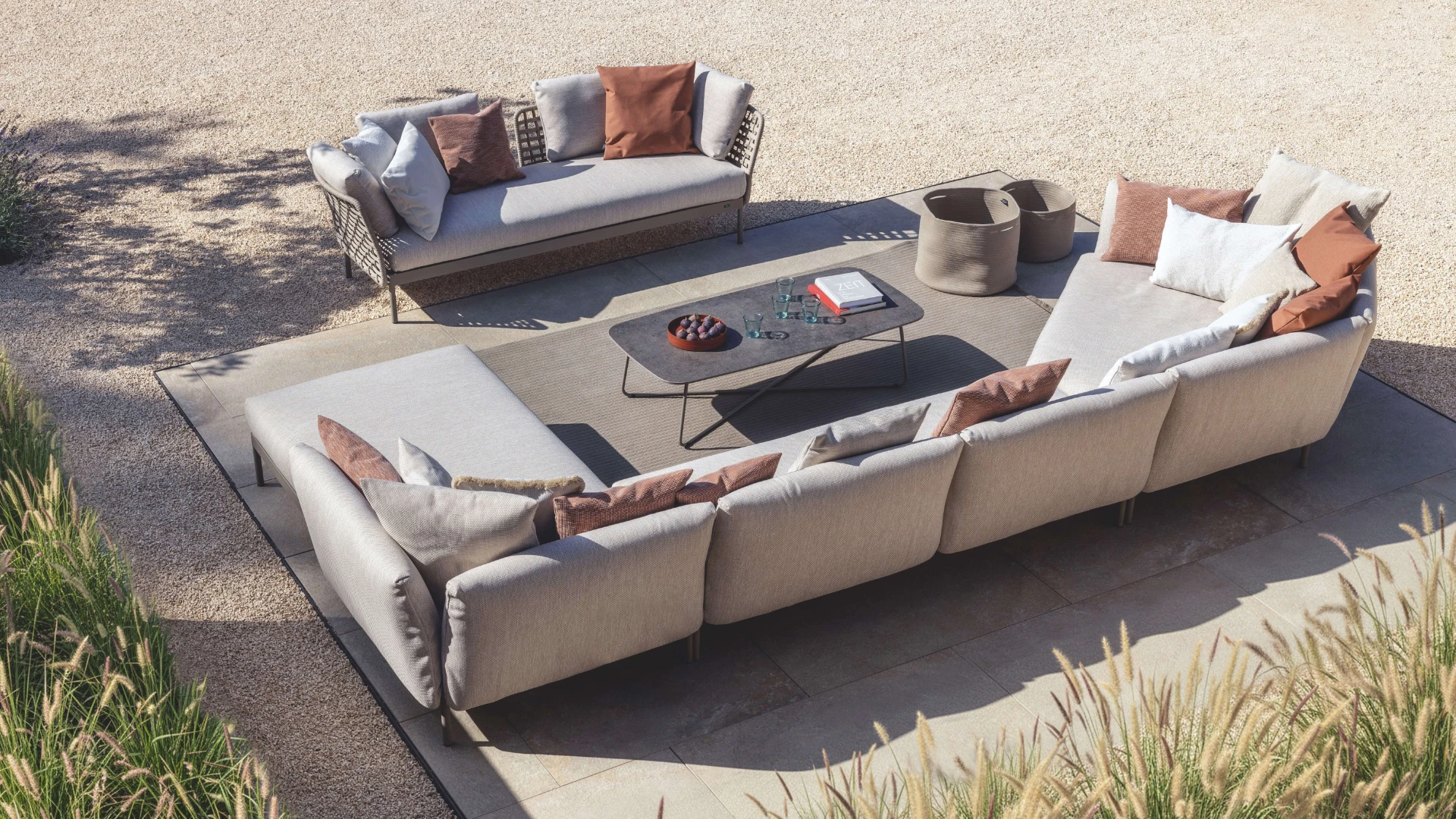 Großzügige Kairos Lounge-Landschaft von Fischer Möbel in der Draufsicht. Modulare Outdoor-Sofas mit feiner Seilflechtung und farblichen Akzentkissen auf einer modernen Designtrasse.