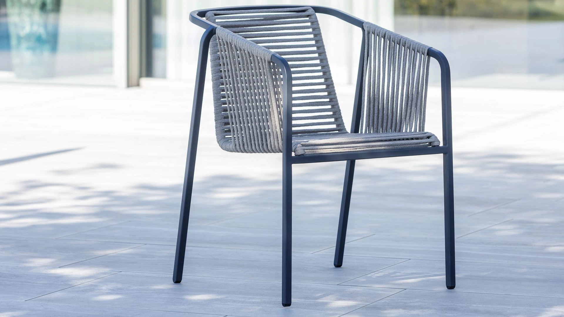 Ein einzelner Suite Sessel mit dunklem Gestell, dunkler Seilbespannung und hellgrauen Sitz- und Rückenkissen vor weißem Hintergrund.