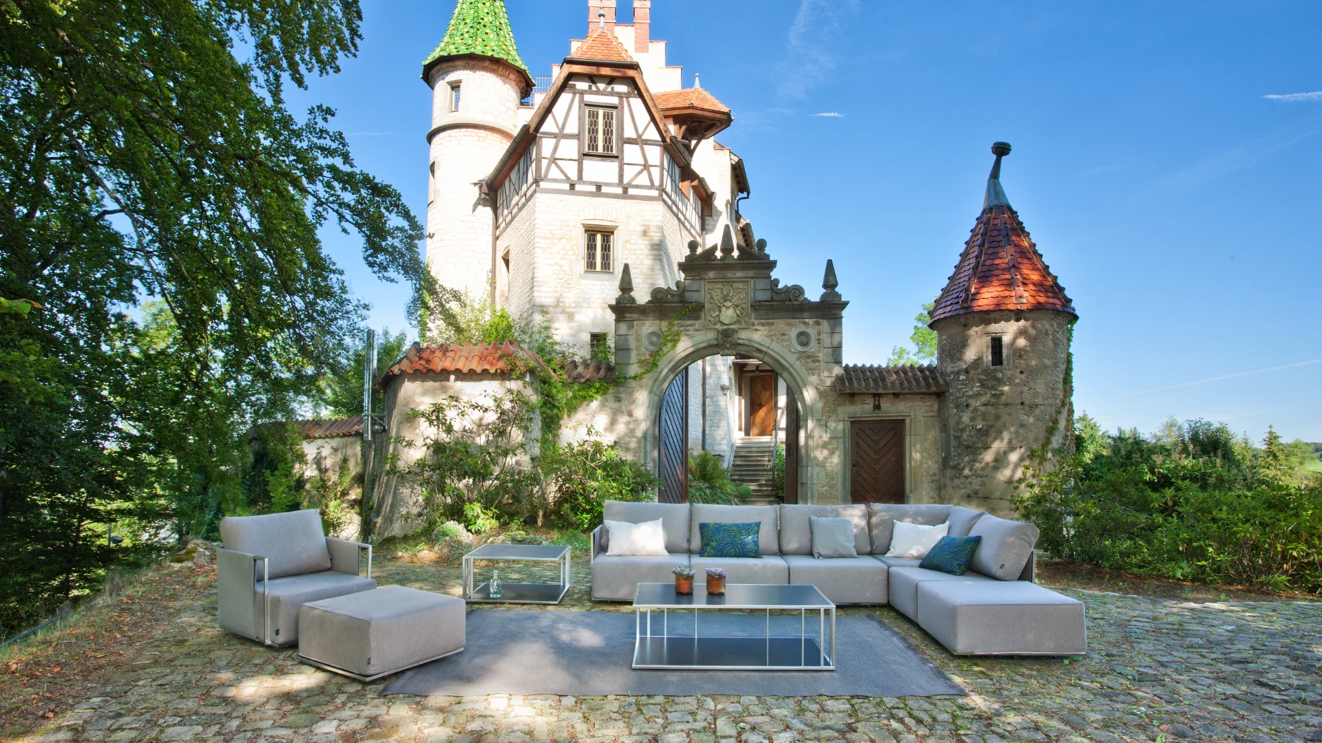 Suite Lounge-Gruppe mit modernen Outdoor-Sofas und Sesseln auf einer Terrasse mit Seeblick bei Abendlicht